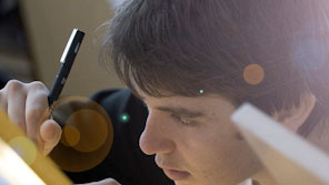 Close up of a student holding a pen and writing on a canvas Close up of a student holding a pen and writing on a canvas