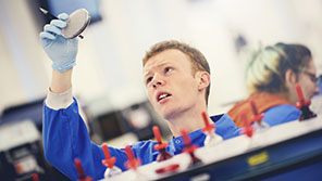 Science student in a lab coat looking at a specimen in a petri dish