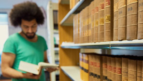 Student looking at a book in a library Student looking at a book in a library