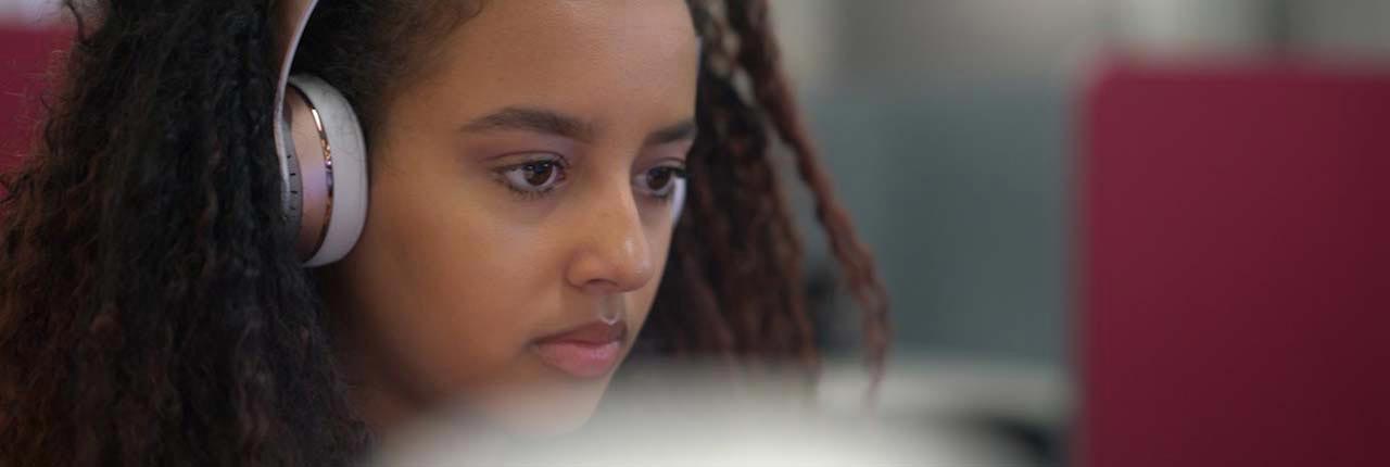 Woman with headphones looking at a screen