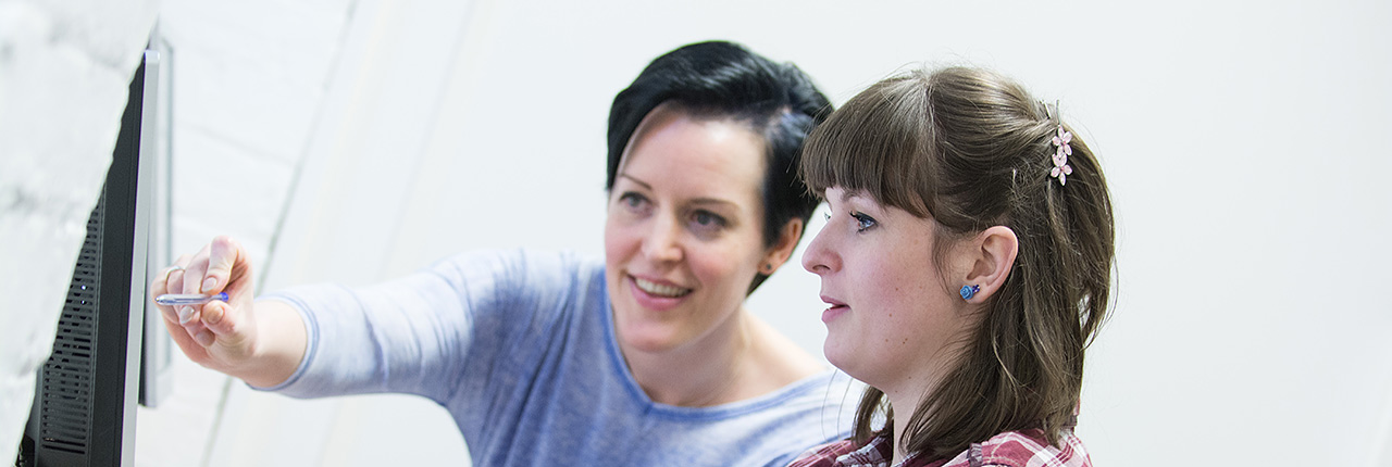 Two students talking while sharing a computer