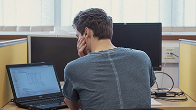 Solitary male student using a computer in a study room Solitary male student using a computer in a study room